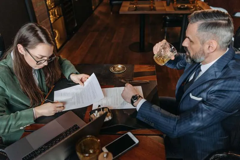 Main tenant un stylo au-dessus d'un devis, cases à cocher et signature prêtes